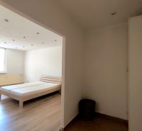Interior of a 1-room apartment with a bed and a wooden decor floor.