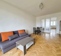 Living room with a sofa, table, and chairs in a 3-room apartment with a wooden decor floor.