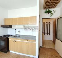 A kitchen in a studio apartment with wooden decor and simple equipment.