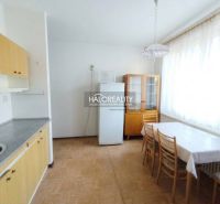 A kitchen in a studio apartment with a dining table and a wooden decor floor.