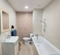 Modern bathroom with a bathtub and sink in a 3-room apartment, light tiles, clean lines.