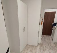 Cozy studio apartment with white furniture and a wood-patterned floor.