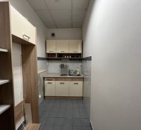 A narrow kitchenette in offices with a dining nook and storage shelves.