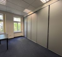 Offices with a large window and a closet, carpet, furniture in neutral colors.