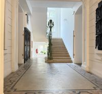 The entrance hall with a decorative floor leads to a staircase with a window.