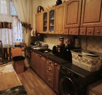 A kitchen in a 2-room apartment with wooden cabinets and appliances.