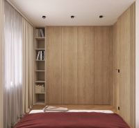 A bedroom with a wooden wardrobe, books, and curtains in a two-room apartment.