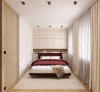 A bedroom in a two-room apartment with a wood-patterned floor and cream curtains.