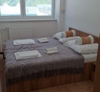 Bedroom with a bed and a window, wooden decor flooring in a 2-room apartment.