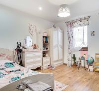 Children's room in a family house with a wooden decor floor and floral furniture.