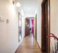 A hallway in a family house with a wooden decor floor and a mirror on the wall.