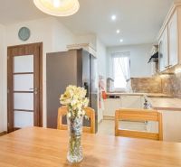 A kitchen in a family house with light furniture and decorative wall cladding.