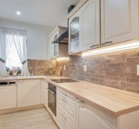 A kitchen in a family house with a wooden decor floor and brick cladding.