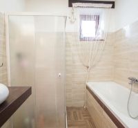 Bathroom with a bathtub, shower, and sink in a family house.