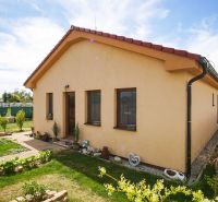 A family house in Andovce with a landscaped garden, yellow facade, and a sloped roof.