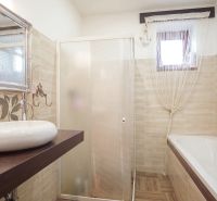 Bathroom in a family house with a bathtub, sink, and shower.