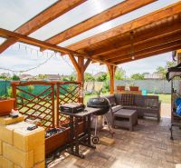 In Andovce, there is a terrace with a grill and furniture under a wooden pergola by the family house.