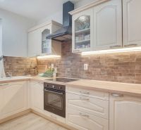A kitchen in a family house with wooden decor and brick cladding on the cabinets.
