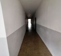 A long hallway with white walls and a tiled floor in a studio apartment.