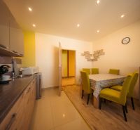 A kitchen in a family house with a wood-patterned floor and yellow chairs.