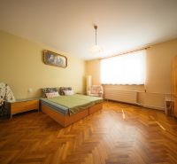 Bedroom in a family house with a bed, wardrobe, and wooden decor flooring.