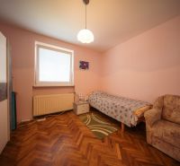 A room in a family house with a bed, a sofa, and a wooden decor floor.