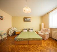 Bedroom in a family house with a bed, chair, and wooden decor flooring.