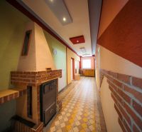 Interior of a family house with a tiled stove, colorful walls, and tiles.