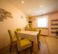 A dining room in a family house with a wooden decor floor and a colorful tablecloth.