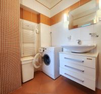 Bathroom with a washing machine and a sink in a 3-room apartment, tiles are in warm shades.