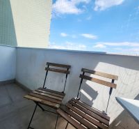 Balcony of a 3-room apartment with two wooden chairs, blue sky, and a protective net.