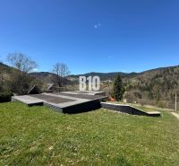 A cottage in Zázrivá with a view of wooded hills and a blue sky.