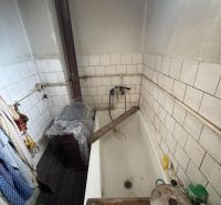 A small bathroom in a family house with white tiles and a bathtub.