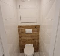 Bathroom section of a 2-room apartment with tiles and cladding in a wooden decor.