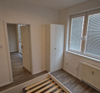 A bedroom in a 2-room apartment with white walls and a wooden decor floor.