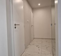 A hallway in a 2-room apartment with white doors and shiny marble tiles.