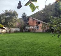 A family house in Poltár surrounded by a lawn and trees in a green environment.