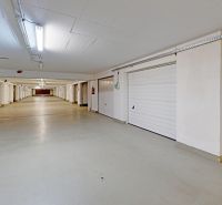Covered garage with sectional doors, white ceiling, and lighting.