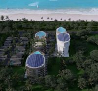 Beachfront apartment development in Phuket with modern buildings and pools surrounded by palm trees.