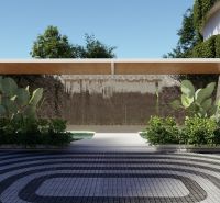 The exterior of an apartment building under construction in Phuket, with foliage and a decorative wall under a canopy.