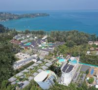 Aerial view of apartment construction near the coast of Phuket with lush greenery.