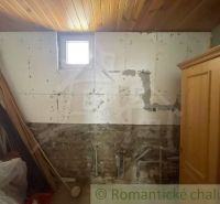 A room with a wooden ceiling, a brick wall, and old furniture in a family house.