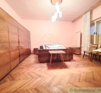 Bedroom in a family house with a wooden decor floor, chandelier, wardrobes, chairs.