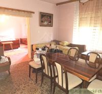 Living room of a family house with a wooden table and a sofa, adjacent room with a bed.