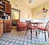 The kitchen of a family house with wooden furniture and tiled floor.
