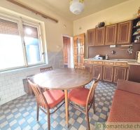A kitchen in a family house with wooden cabinets and a tiled floor.