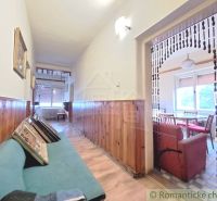 A hallway in a family house with wooden paneling and a view into the dining room.