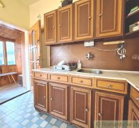 A kitchen in a family house with wooden cabinets and a tiled floor.