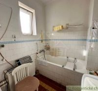 A bathroom in a family house with a bathtub, a window, and tiles.
