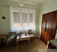 A room in a family house with lace curtains and a wooden table.